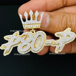 May include: A gold pendant with a crown on top and the number "7307" set with diamonds. The pendant is held in a hand. The text "STAR JEWELLERY" appears twice on the image.