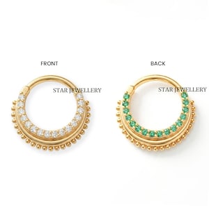 May include: Two gold-colored septum rings. One ring features clear gemstones, the other features green gemstones. The text "STAR JEWELLERY" is printed on each ring. The rings are displayed against a white background.