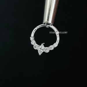 May include: A silver hoop earring with a marquise-shaped diamond and smaller round diamonds set in a row. The earring is held by a tool with the text "STAR JEWELLERY" visible.