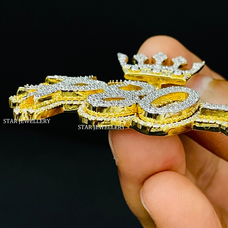 May include: A gold pendant with a crown and the word "Boss" set with clear cubic zirconia stones.