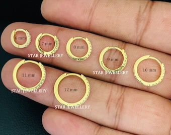 May include: A set of 10 gold hoop earrings with a row of clear cubic zirconia stones. The earrings are displayed on a hand, with each hoop labeled with its diameter in millimeters: 6 mm, 7 mm, 8 mm, 9 mm, 10 mm, 11 mm, and 12 mm.  STAR JEWELLERY is printed below each hoop.