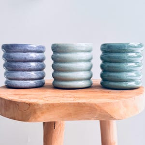 Może przedstawiać: Rustykalny drewniany szyld z napisem "Welcome to our home" w białych literach. Szyld ma postarzaną powierzchnię i prosty, zapraszający design, idealny do dekoracji wejścia.