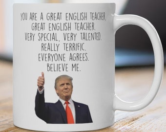 May include: White ceramic mug with a black handle. The mug features text that reads, "YOU ARE A GREAT ENGLISH TEACHER, GREAT ENGLISH TEACHER, VERY SPECIAL, VERY TALENTED, REALLY TERRIFIC, EVERYONE AGREES, BELIEVE ME." An image of a man in a suit is also on the mug.