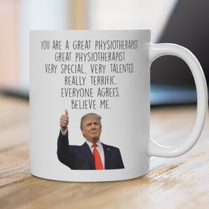 Puede incluir: Taza de cerámica blanca con el texto "YOU ARE A GREAT PHYSIOTHERAPIST" y una imagen de un hombre haciendo una señal de pulgar hacia arriba. La taza también incluye las frases "VERY SPECIAL, VERY TALENTED, REALLY TERRIFIC, EVERYONE AGREES, BELIEVE ME."