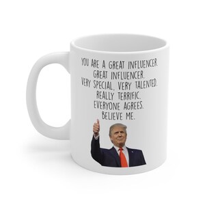 May include: White ceramic mug with a black handle. The mug features text that reads "YOU ARE A GREAT INFLUENCER. GREAT INFLUENCER. VERY SPECIAL, VERY TALENTED. REALLY TERRIFIC. EVERYONE AGREES. BELIEVE ME." and an image of a man giving a thumbs up.