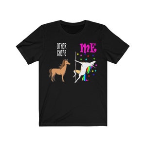 May include: Black t-shirt with a humorous graphic. The design features a brown horse labeled "OTHER CHEFS" and a unicorn pole dancing labeled "ME". The unicorn has a rainbow mane and tail, with colorful stars.