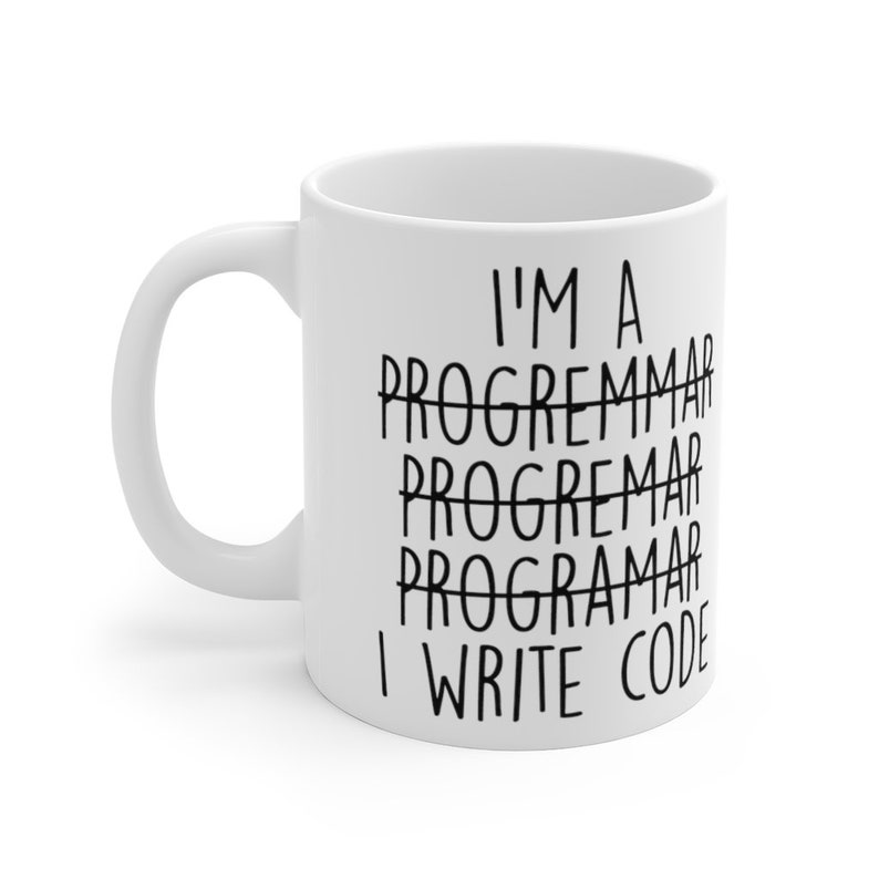 May include: White ceramic mug with a curved handle. The mug features the text "I'M A PROGRAMMAR, I WRITE CODE" in black, with the word "PROGRAMMAR" crossed out multiple times. A humorous gift for programmers.