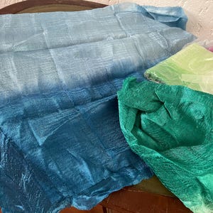 May include: Three pieces of fabric in shades of blue, green, and light green. The fabric is sheer and has a silky texture.