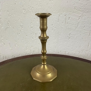 Puede incluir: Un candelero de latón con una base octogonal y un tallo detallado. El candelero tiene un diseño clásico y un color dorado cálido. Es un artículo decorativo adecuado para sostener una sola vela, agregando un toque de elegancia.