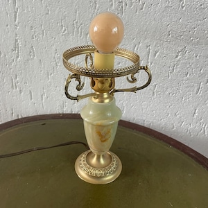 May include: A green and gold table lamp with a white glass shade. The lamp has a decorative base and a round shade.