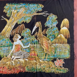 Puede incluir: Un tapiz de pared de tela negra con un diseño batik colorido. El diseño presenta un pájaro, una mujer y follaje en tonos de verde, azul, dorado y rojo.