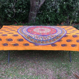Puede incluir: Mantel de mesa naranja con un gran diseño de mandala colorido en el centro. El mantel está hecho de algodón y tiene un patrón de paisley alrededor de los bordes.