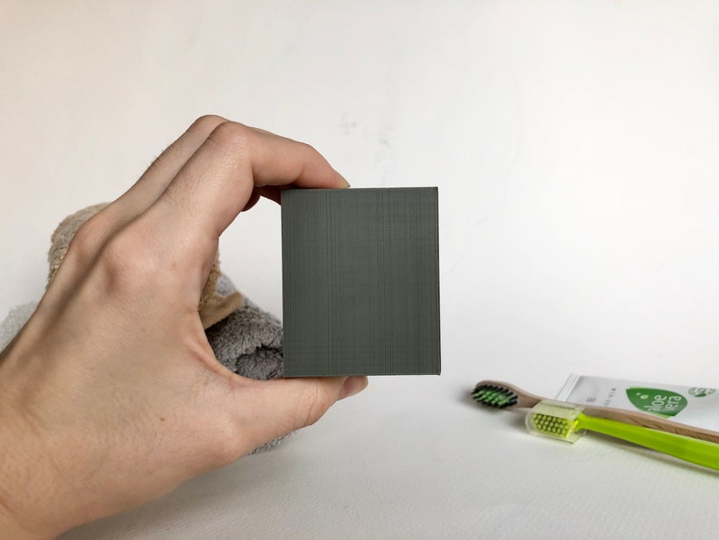 May include: A dark gray rectangular bar of soap.