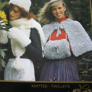 May include: Two people modelling knitted winter wear. One wears a white hat, scarf, and mittens; the other a grey cape and purse. The image features the text "KNITTED • TWILLEYS". The style appears to be vintage.