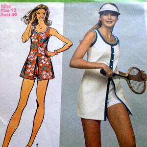 May include: A sewing pattern envelope featuring a sleeveless tennis dress with a front button placket and matching shorts. The illustration shows a floral print version, while the photograph displays a white dress with blue trim and a visor.