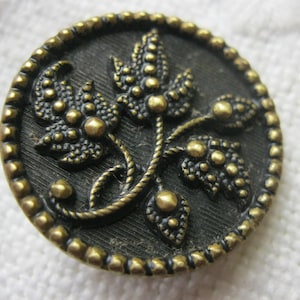 Antique  brass  button with brass loop shank 1" dia has cut steel effect for the makeup of the leaves