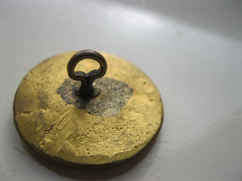Antique brass button featuring dragon has brass loop shank and measures 1.18 dia