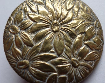 Antique dull gold floral metal button with black base and loop shank 1" dia