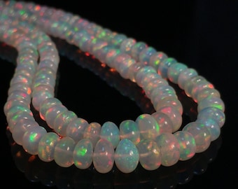 Könnte beinhalten: Eine Kette aus weißen Opalperlen mit schillernden Farbflecken. Die Perlen sind rund und glatt, und die Kette ist etwa 45 cm lang.