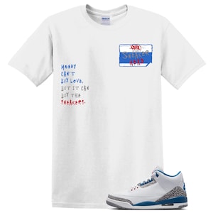 May include: A white short-sleeve t-shirt featuring a blue name tag graphic that reads Hello My Name Is SNEAKER HEAD and text that reads MONEY CAN'T BUY LOVE, BUT IT CAN BUY THE SNEAKERS. A white, blue, and grey sneaker is positioned at the bottom right.