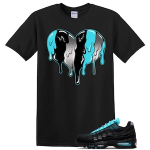 May include: A black short-sleeve t-shirt featuring a large graphic of a melting heart in shades of black, white, and bright cyan blue. Below the shirt is a black athletic sneaker with cyan blue laces and a visible air cushioning unit in the sole.