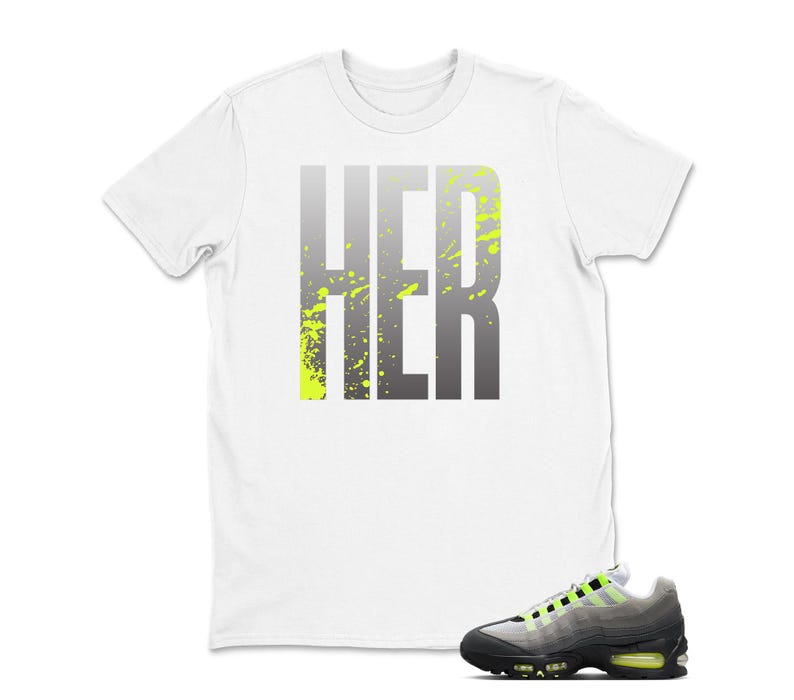Puede incluir: Camiseta blanca con la palabra "HER" en degradado gris y salpicaduras verde ne&oacute;n. Un par de zapatillas deportivas grises, negras y verde ne&oacute;n est&aacute;n en primer plano, complementando el dise&ntilde;o de la camiseta.
