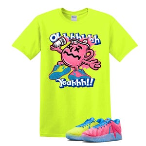 May include: A neon yellow t-shirt featuring a pink cartoon character holding a white object, with the text "Oh Yeahhh!!" in blue and white. The character is wearing blue and pink sneakers. A pair of matching sneakers are at the bottom.