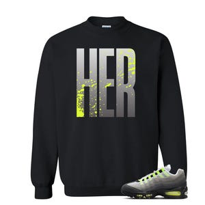 Puede incluir: Sudadera negra con la palabra "HER" en letras grandes, grises y amarillo ne&oacute;n. Un par de zapatillas grises, negras y amarillo ne&oacute;n en la parte inferior de la imagen.