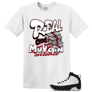 May include: A white short-sleeve t-shirt featuring a graphic print of a stack of cash and the text "REAL ONES MOVE IN SILENCE" in bold white and red lettering, accompanied by a white and black high-top athletic sneaker positioned at the bottom.