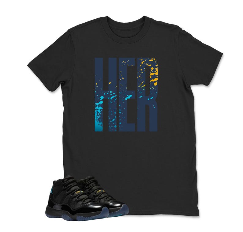 Op de afbeelding: Zwart T-shirt met het woord "HER" in een blauw en geel spatterontwerp. Een paar zwarte en blauwe sneakers staan onderaan de afbeelding.