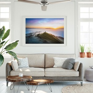 May include: A framed photograph of a hilltop with a tower at the peak, surrounded by fog and a colorful sunrise in the background.