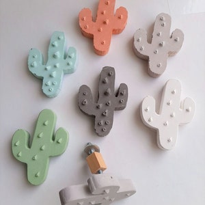 Può includere: Sei tiretti per cassetti a forma di cactus di diversi colori, con un settimo tiretto a forma di cactus con un pomello in legno. I tiretti sono realizzati in materiale grigio chiaro, bianco, verde chiaro, verde scuro, blu chiaro e arancione.