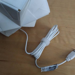 May include: White origami-style lamp with a white USB cord and plug.