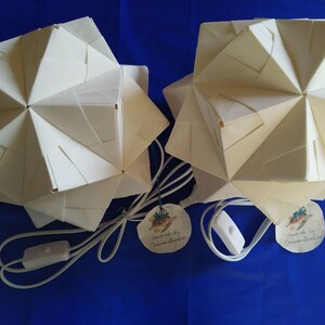 May include: Two white origami paper lamps with a white cord and on/off switch. Each lamp has a round paper tag with a turtle design and the text "Handmade by OceanMoonStudio.com".