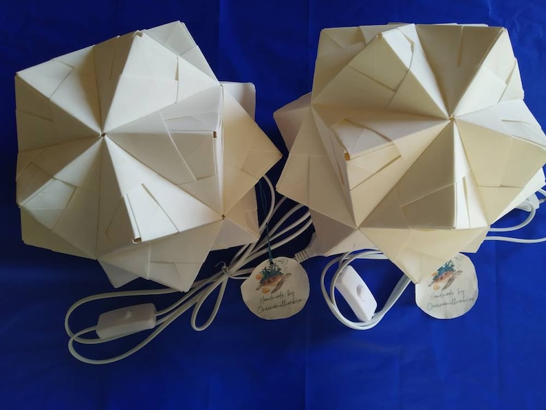 May include: Two white origami paper lamps with a white cord and on/off switch. Each lamp has a round paper tag with a turtle design and the text "Handmade by OceanMoonStudio.com".