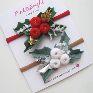 May include: Two elastic headbands on a white display card labeled Pink & Bright Handmade and Shine bright like a Diamond. One headband features red felt berries and green leaves, the other has white felt berries and green leaves.