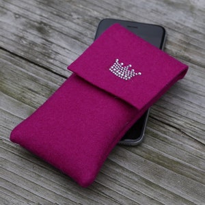 May include: A fuchsia felt phone case with a silver rhinestone crown design.