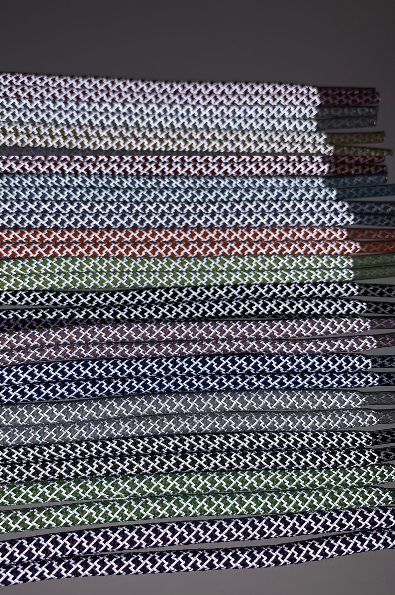 Puede incluir: Una colecci&oacute;n de cordones de zapatos en varios colores, cada uno con un patr&oacute;n de diamante blanco. Los cordones est&aacute;n dispuestos en una pila, con la parte superior de la pila siendo la adici&oacute;n m&aacute;s reciente.