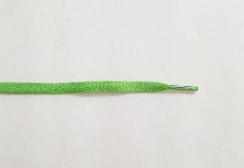 May include: A bright green shoelace with a silver aglet.