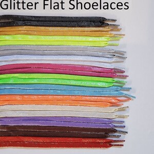 May include: A variety of flat shoelaces with glitter. The shoelaces are arranged in rows, with each row a different color. The colors include black, gold, neon green, white, pink, lime green, light blue, orange, silver, lavender, brown, and red.