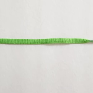 Puede incluir: Un cord&oacute;n de zapato verde brillante sobre un fondo blanco.