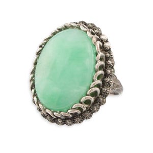 May include: A silver ring with a large oval green jade stone set in a detailed silver filigree design.