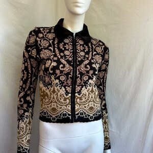 May include: A black and brown patterned cardigan with a zipper closure. The cardigan has a collar and long sleeves.