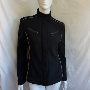 May include: A black jacket with a high collar and zipper closure. The jacket has a slim fit and features a contrasting beige trim along the seams and pockets.