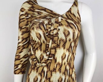 May include: A brown and white leopard print top with one long sleeve and one short sleeve. The top has a draped neckline and a fitted silhouette.