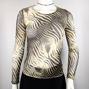 Pode incluir: Uma blusa transparente de manga comprida com estampa de zebra em preto e bege.