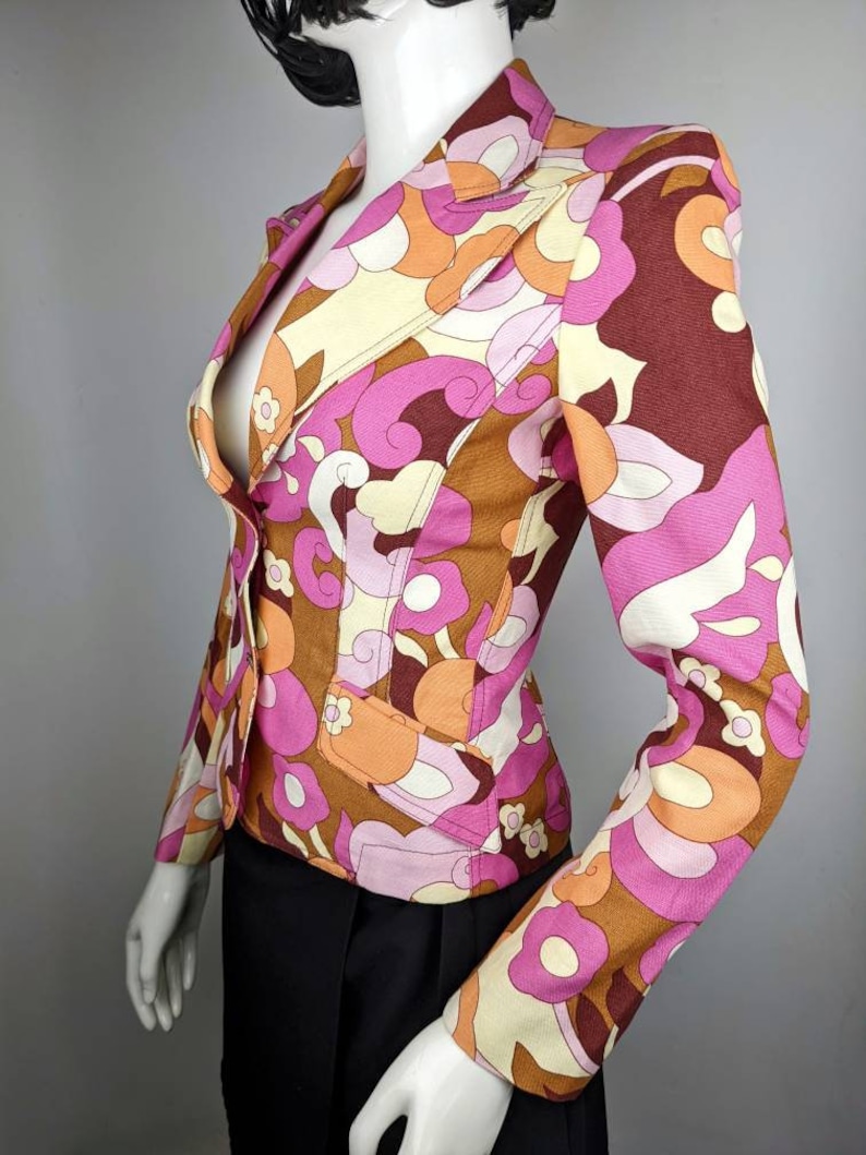 May include: A pink, brown, and orange patterned blazer with a button closure. The blazer has a fitted silhouette and long sleeves.