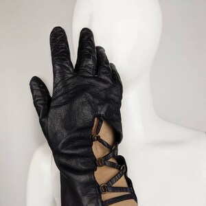 May include: Black leather gloves with a lace-up detail and metal accents on the wrist.