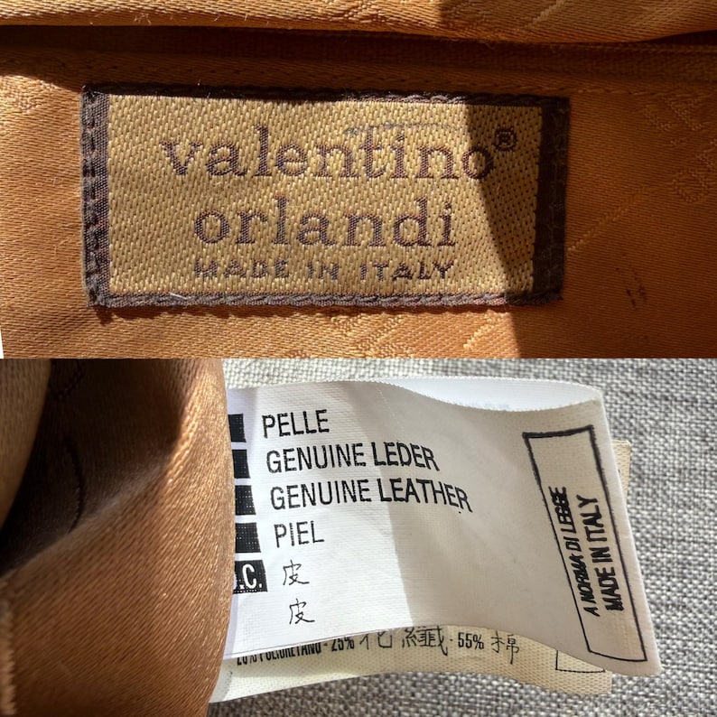Puede incluir: Una etiqueta rectangular de tela marr&oacute;n con el texto bordado valentino orlandi MADE IN ITALY. Una etiqueta blanca de cuidado enumera materiales en varios idiomas, incluyendo PELLE, GENUINE LEATHER, PIEL, e incluye A NORMA DI LEGGE MADE IN ITALY.