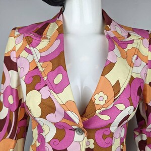 May include: A brown, pink, orange, and white patterned blazer with a single button closure. The blazer has a collar and long sleeves.